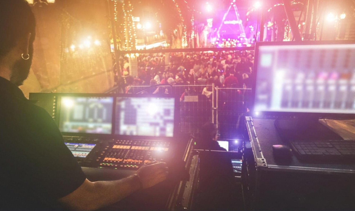 Technical operator running lighting and sound desks at a live UAE event with a crowd in the background
